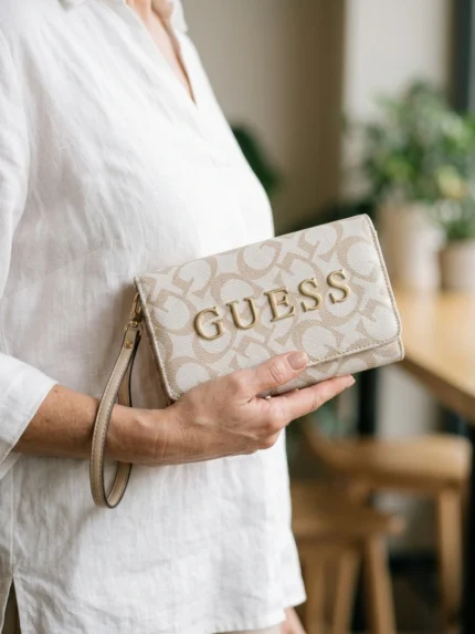 Guess blanca y beige con monograma y letras GUESS doradas grandes — en la mano